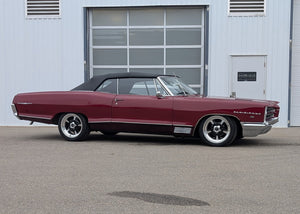 Maroon 1966 Parisienne parked in front of a gray building with a garage door.