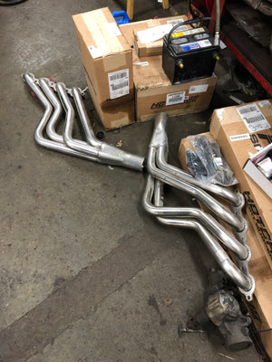 Metal exhaust pipes on a concrete floor with boxes and tools in the background