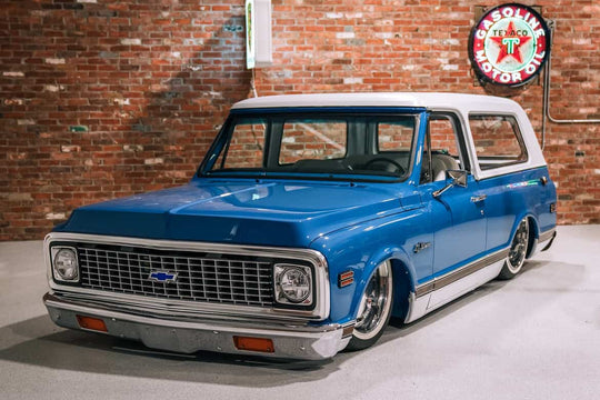 Blue vintage 1972 Chevrolet Blazer in a showroom with brick wall and neon signs.