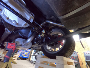 Close-up of a motorcycle undercarriage with tools and equipment in a workshop setting.