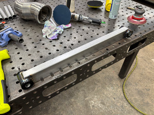 Fabricated lower 4 link bar for chassis assembly sitting on work bench