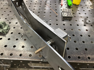 Metal frame assembly on a perforated metal surface with tools in the background