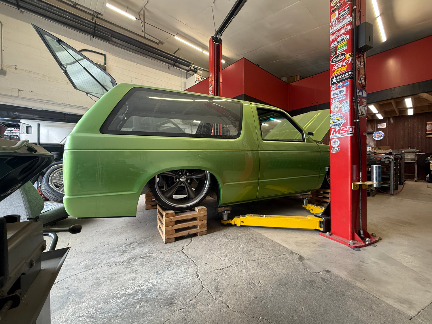 Green 1991 Jimmy on a lift in a garage with various tools and equipment around