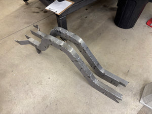 Assembled chassis rails on a concrete floor with a chair and toolbox in the background