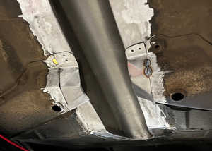 Close-up of a vehicle's undercarriage with metal components and rust.