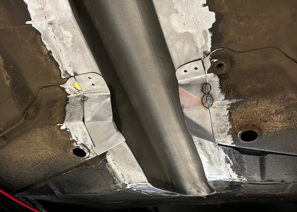 Close-up of a vehicle's undercarriage with metal components and rust.