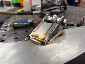 Metal component on a workbench with tools in the background