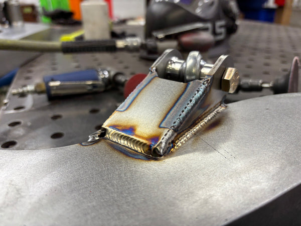 Metal component on a workbench with tools in the background
