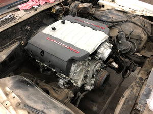 Car engine with 'Camaro' branding on a mechanical workspace.