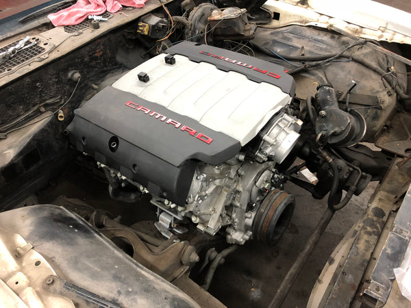 Car engine with 'Camaro' branding on a mechanical workspace.