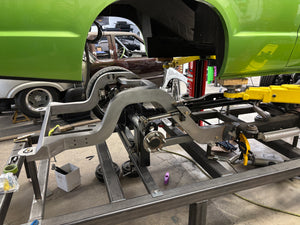 Automotive repair work on a vehicle chassis in a workshop.