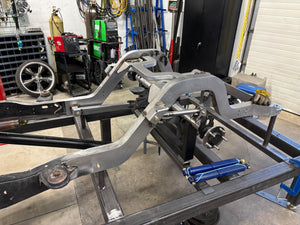 Metal vehicle frame with suspension components in a workshop setting