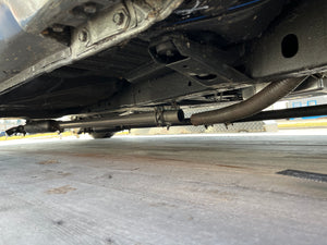 Close-up of a vehicle's undercarriage with exhaust pipes and suspension components.