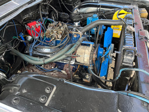 Car engine compartment with various components and wiring.