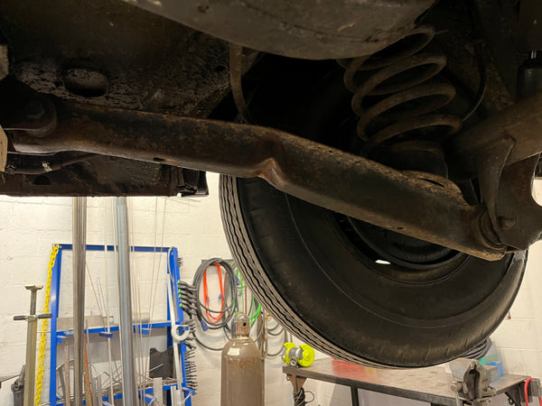 Close-up of a vehicle's suspension system with a tire on a lift.