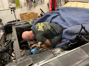 Person working on a vehicle engine in a garage.