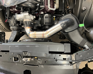 Close-up of a car engine with a metallic exhaust pipe and various mechanical components.