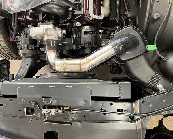 Close-up of a car engine with a metallic exhaust pipe and various mechanical components.