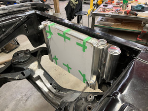 Radiator with green tape in a vehicle frame, workshop setting