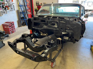 Car chassis in a workshop setting with tools and equipment in the background