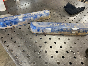 Two blue metal objects on a perforated metal surface