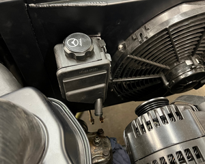 Close-up of a car engine with visible components like the alternator and air filter.