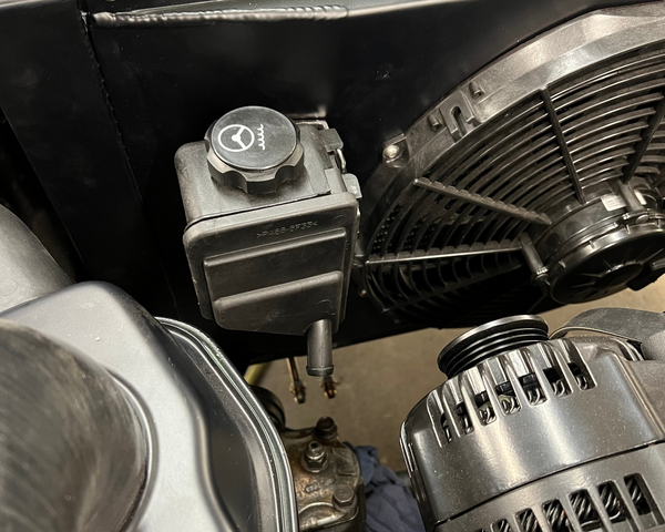 Close-up of a car engine with visible components like the alternator and air filter.