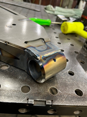 Metal component on a workbench with tools in the background