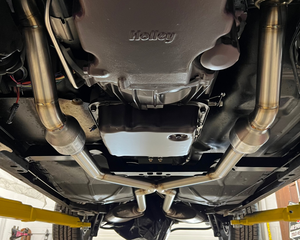 Undercarriage of a vehicle with 'Helwig' branding in a garage setting.