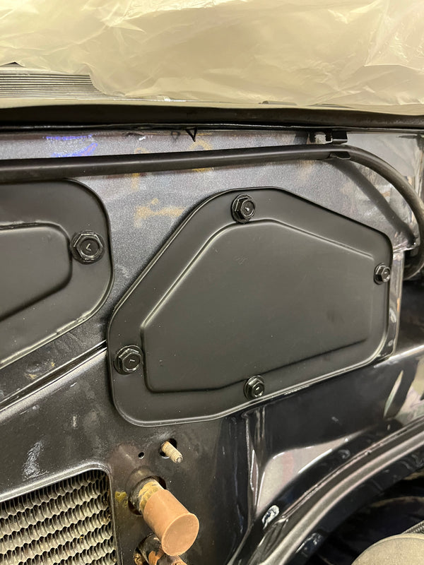 Close-up of a vehicle's side panel with a black cover and visible components.