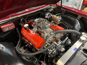 Close-up of a red Chevrolet engine in a vehicle's open hood.