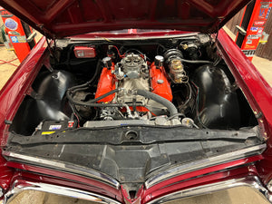 Car engine compartment with red interior and visible components.