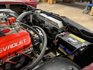 Close-up of a Chevrolet engine and battery in a workshop setting
