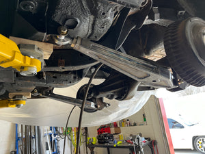 Close-up of a vehicle's undercarriage with suspension components in a garage setting.