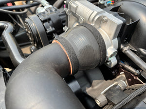 Close-up of automotive engine components with a focus on a black rubber hose.