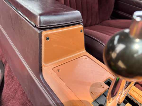 Close-up of a car interior with a wooden panel and metallic object.