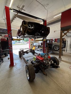 Parisienne on a lift in a garage with various tools and equipment around