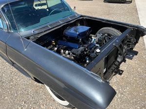 Car engine compartment with open hood on a concrete surface