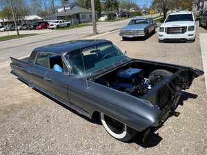 Vintage Cadillac with its hood open on a street