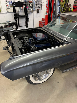 Cadillac with open hood in a garage setting