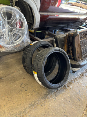 Stack of tires and car rims on a concrete surface