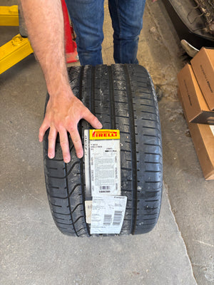 Person holding a tire with visible branding on a concrete surface