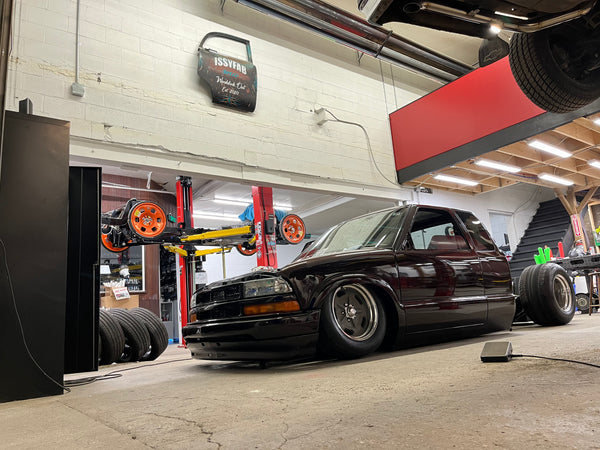 Black car on a lift in a garage with various equipment around
