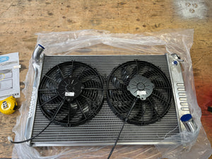 Radiator with fans on a wooden surface, partially covered by plastic wrap.