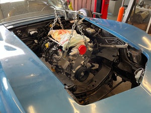 Car engine exposed with tools and parts in a workshop setting