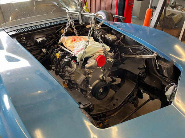 Car engine exposed with tools and parts in a workshop setting