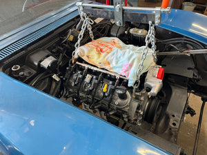 Car engine being worked on with a towel over it, inside a vehicle.
