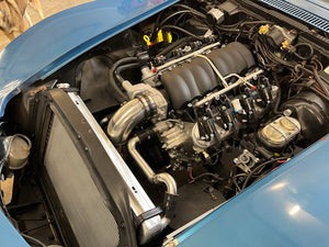 Car engine compartment with visible components and blue car exterior.