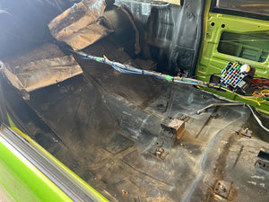 Interior of a vehicle with exposed wiring and components, showing signs of wear and tear.