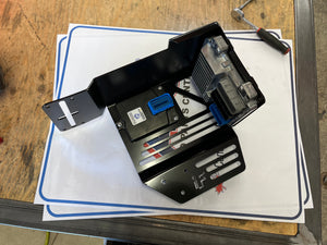 Mechanical component on a white sheet of paper with blue border on a wooden surface